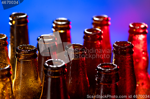 Image of Neon colored beer bottles. Close up on bright studio background