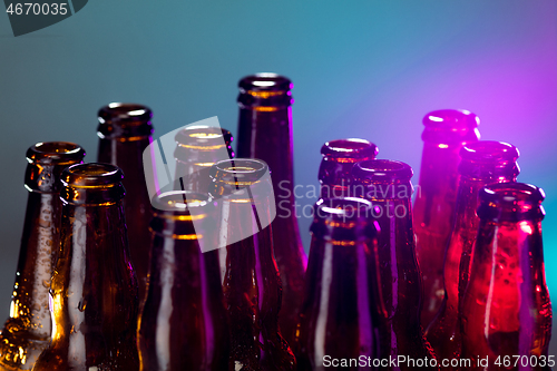 Image of Neon colored beer bottles. Close up on bright studio background