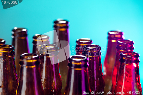 Image of Neon colored beer bottles. Close up on bright studio background