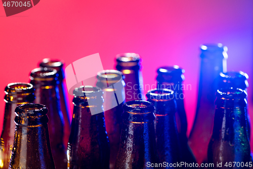 Image of Neon colored beer bottles. Close up on bright studio background