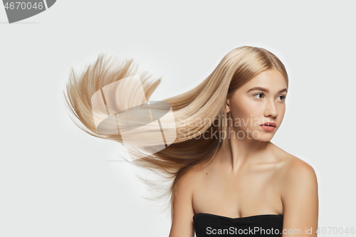 Image of Beautiful model with long smooth, flying blonde hair isolated on white studio background.