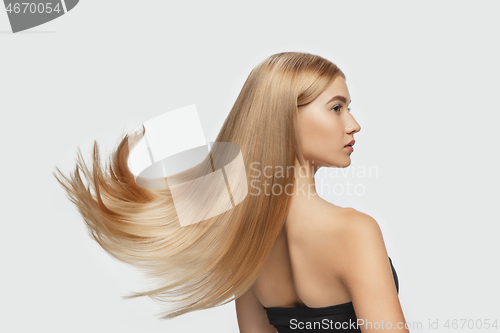 Image of Beautiful model with long smooth, flying blonde hair isolated on white studio background.