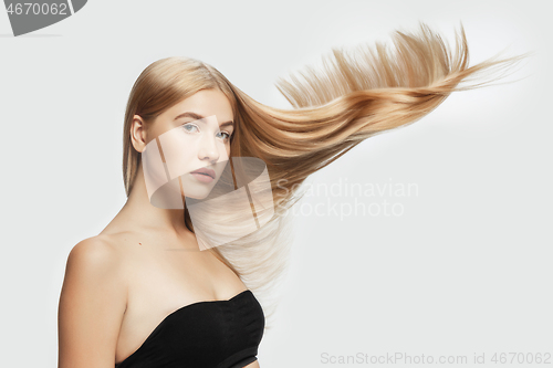 Image of Beautiful model with long smooth, flying blonde hair isolated on white studio background.