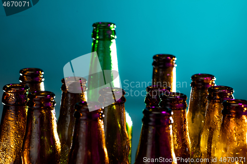 Image of Neon colored beer bottles. Close up on bright studio background