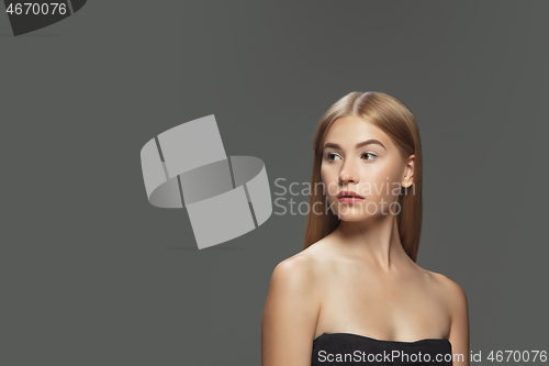 Image of Beautiful model with long smooth, flying blonde hair isolated on dark studio background.