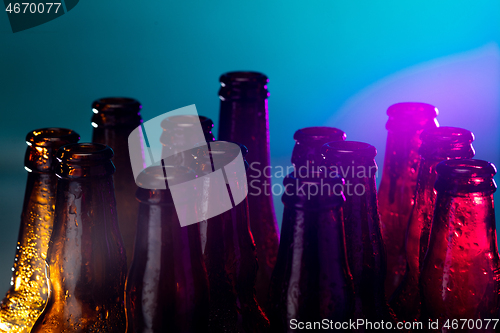 Image of Neon colored beer bottles. Close up on bright studio background