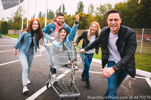 Image of Group of four young diverse friends in jeanse outfit look carefree, young and happy on city\'s streets