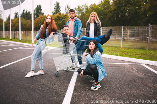 Image of Group of four young diverse friends in jeanse outfit look carefree, young and happy on city\'s streets