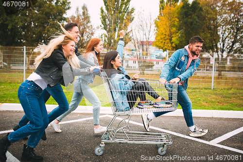 Image of Group of four young diverse friends in jeanse outfit look carefree, young and happy on city\'s streets