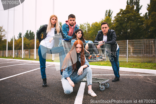 Image of Group of four young diverse friends in jeanse outfit look carefree, young and happy on city\'s streets