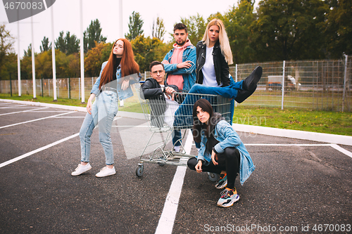 Image of Group of four young diverse friends in jeanse outfit look carefree, young and happy on city\'s streets