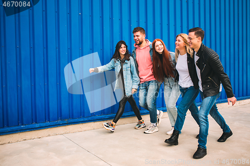 Image of Group of four young diverse friends in jeanse outfit look carefree, young and happy on city\'s streets