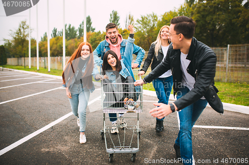 Image of Group of four young diverse friends in jeanse outfit look carefree, young and happy on city\'s streets