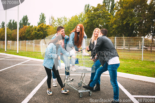 Image of Group of four young diverse friends in jeanse outfit look carefree, young and happy on city\'s streets