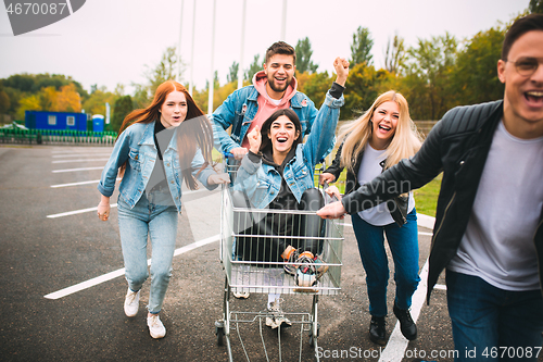 Image of Group of four young diverse friends in jeanse outfit look carefree, young and happy on city\'s streets