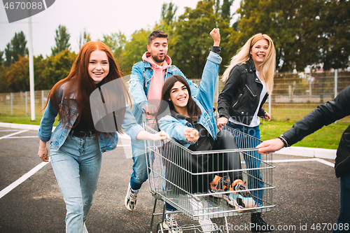 Image of Group of four young diverse friends in jeanse outfit look carefree, young and happy on city\'s streets