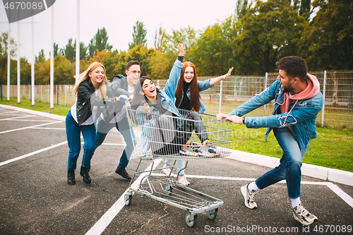 Image of Group of four young diverse friends in jeanse outfit look carefree, young and happy on city\'s streets