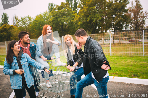 Image of Group of four young diverse friends in jeanse outfit look carefree, young and happy on city\'s streets