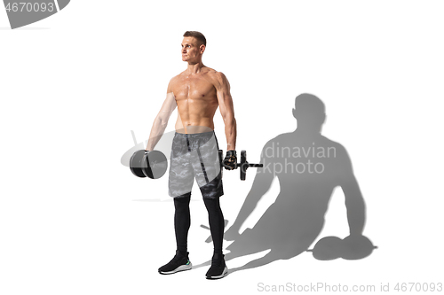 Image of Beautiful young male athlete practicing on white studio background with shadows