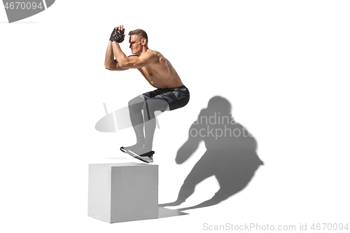 Image of Beautiful young male athlete practicing on white studio background with shadows