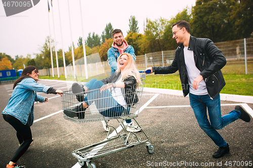 Image of Group of four young diverse friends in jeanse outfit look carefree, young and happy on city\'s streets