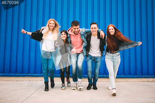 Image of Group of four young diverse friends in jeanse outfit look carefree, young and happy on city\'s streets