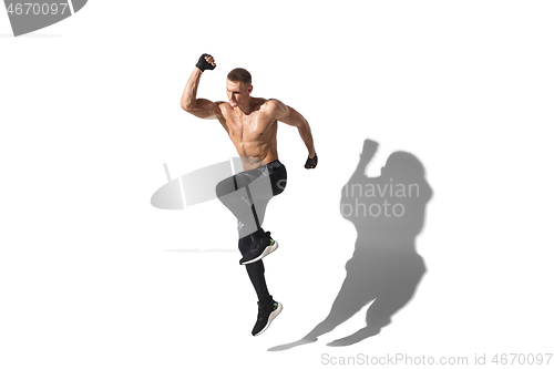 Image of Beautiful young male athlete practicing on white studio background with shadows