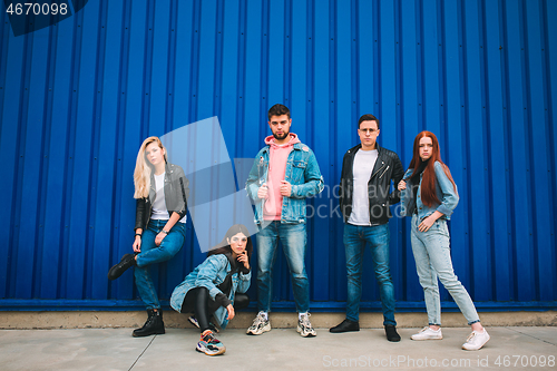 Image of Group of four young diverse friends in jeanse outfit look carefree, young and happy on city\'s streets