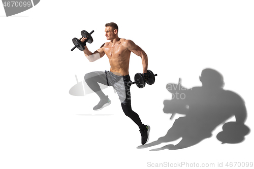 Image of Beautiful young male athlete practicing on white studio background with shadows