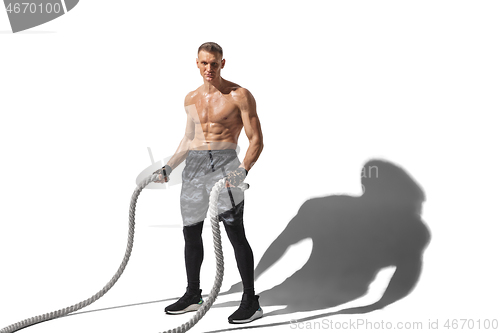 Image of Beautiful young male athlete practicing on white studio background with shadows