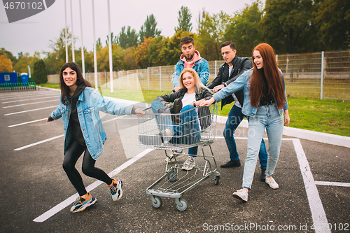 Image of Group of four young diverse friends in jeanse outfit look carefree, young and happy on city\'s streets