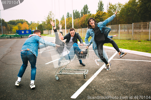 Image of Group of four young diverse friends in jeanse outfit look carefree, young and happy on city\'s streets