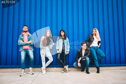 Image of Group of four young diverse friends in jeanse outfit look carefree, young and happy on city\'s streets