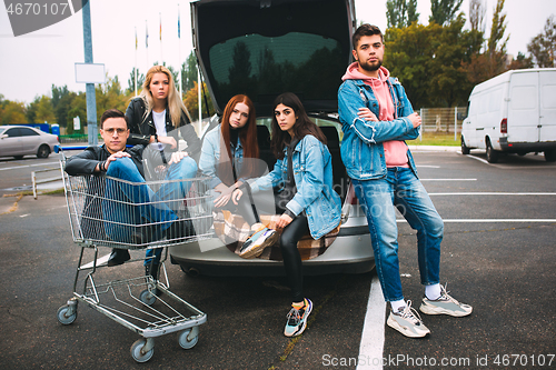 Image of Group of four young diverse friends in jeanse outfit look carefree, young and happy on city\'s streets