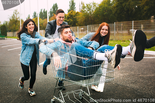 Image of Group of four young diverse friends in jeanse outfit look carefree, young and happy on city\'s streets