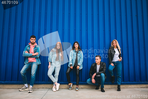 Image of Group of four young diverse friends in jeanse outfit look carefree, young and happy on city\'s streets