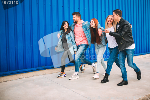 Image of Group of four young diverse friends in jeanse outfit look carefree, young and happy on city\'s streets