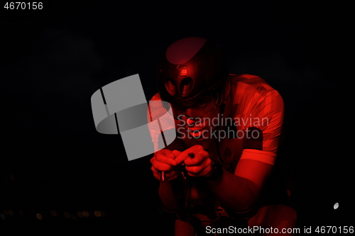 Image of triathlon athlete riding bike fast at night