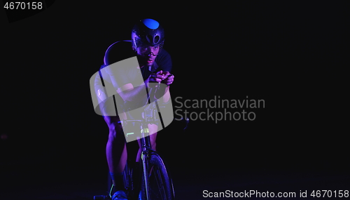 Image of triathlon athlete riding bike fast at night