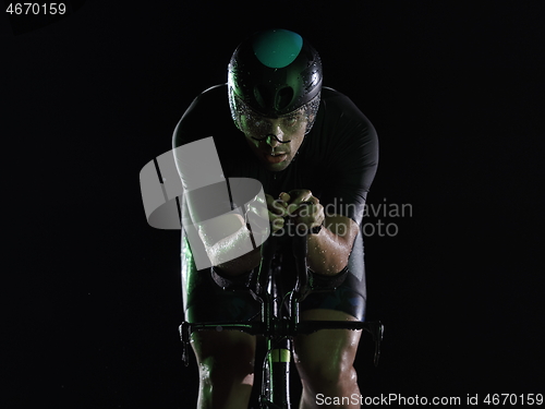 Image of triathlon athlete riding bike fast at night