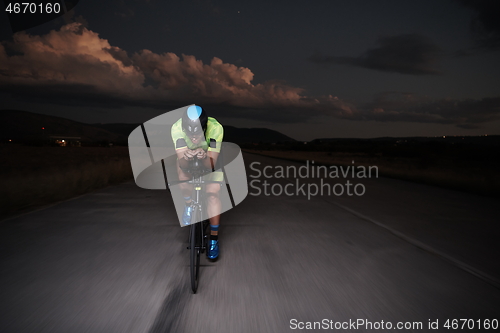 Image of triathlon athlete riding bike fast at night