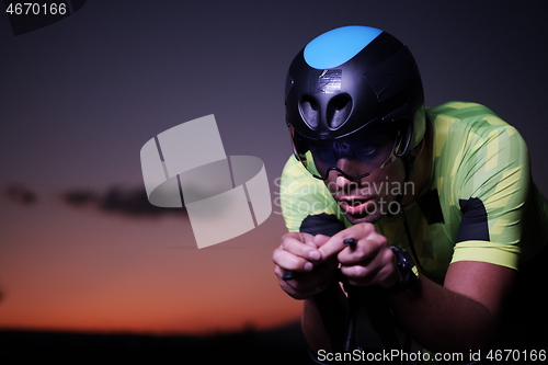 Image of triathlon athlete riding bike fast at night