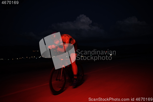 Image of triathlon athlete riding bike fast at night