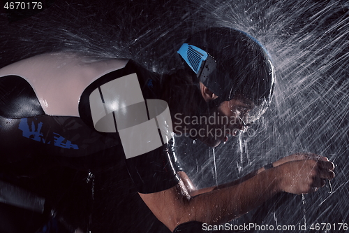 Image of triathlon athlete riding bike fast on rainy night