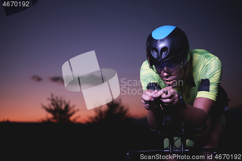 Image of triathlon athlete riding bike fast at night