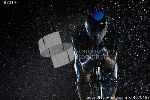 Image of triathlon athlete riding bike fast on rainy night