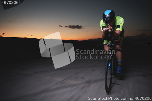 Image of triathlon athlete riding bike fast at night