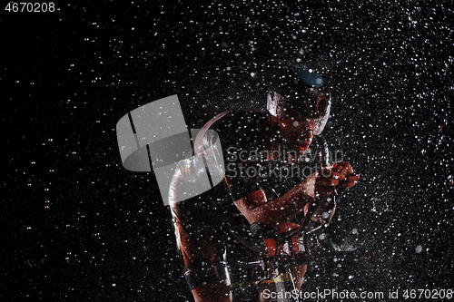 Image of triathlon athlete riding bike fast on rainy night