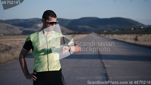 Image of triathlon athlete resting and setting smartwatch