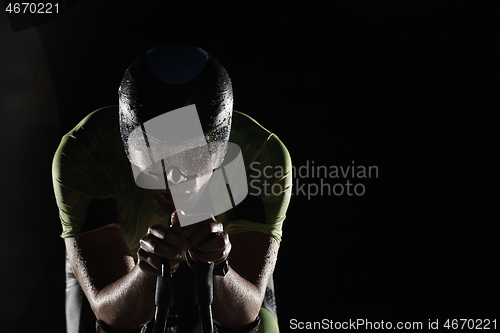 Image of triathlon athlete riding bike fast at night